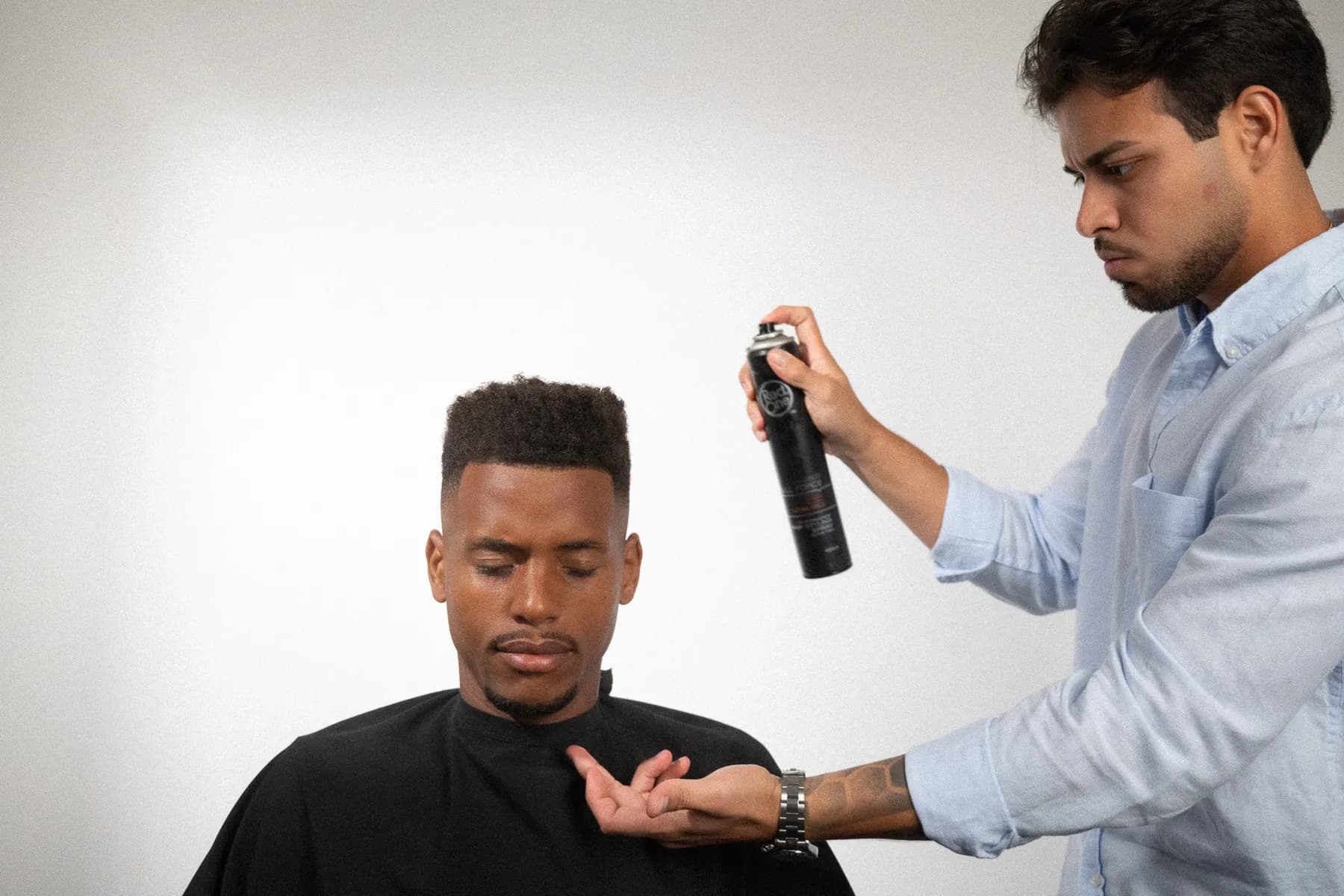 Barbero mostrando al cliente el producto de acabado que usa