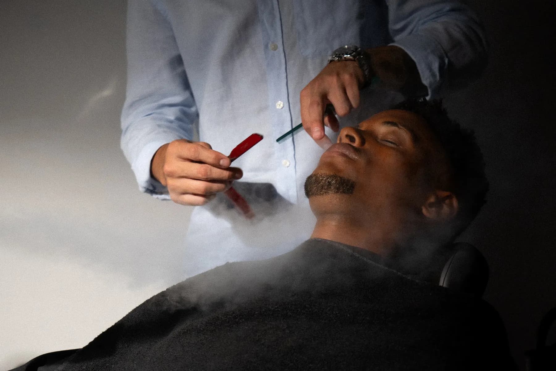 Barbero perfilando la barba a navaja con toalla caliente